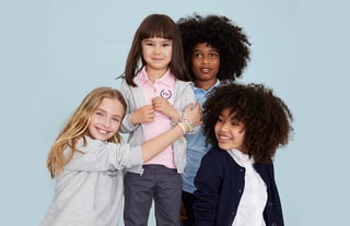 a group of four kids wearing embroidered school uniforms